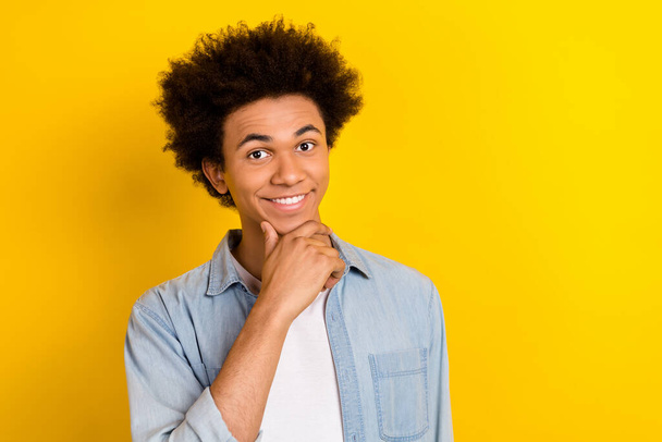 Photo of cheerful thoughtful man wear jeans shirt arm chin empty space isolated yellow color background. - Fotó, kép