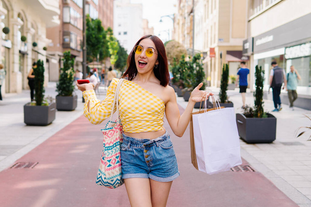 Frontalny portret stylowej szczęśliwej kobiety z torbami na zakupy na ulicy - Zdjęcie, obraz