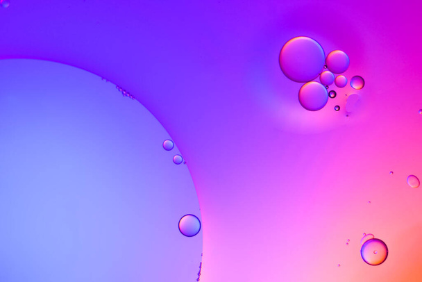 Top view movement of oil bubbles in the liquid. Oil surface multicolored background. Fantastic structure of colorful bubbles. Colorful artistic image of oil drop floating on the water - Φωτογραφία, εικόνα