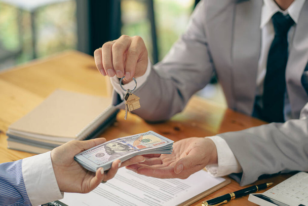 Verkoper overhandigt sleutels aan klant Nieuwe woningkopers worden goedgekeurd voor woningkredieten en verzekeringscontracten. - Foto, afbeelding