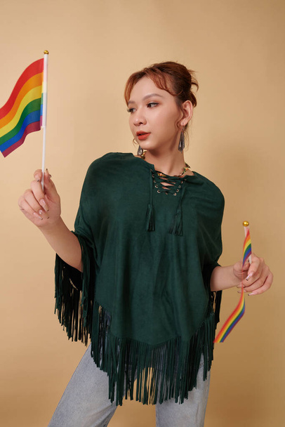 Młoda transseksualistka pozująca z dwiema tęczowymi flagami, koncepcja miesiąca dumy - Zdjęcie, obraz