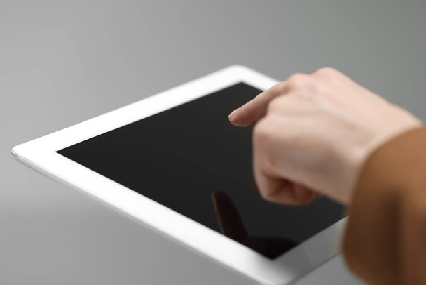 Closeup view of woman using modern tablet on light grey background - Foto, immagini