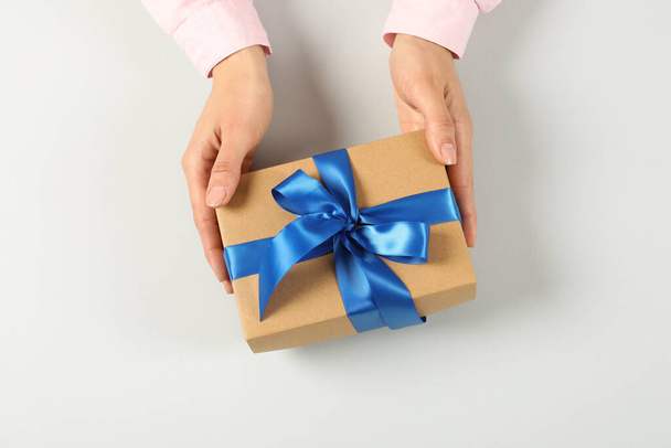 Woman holding gift box on light background, top view - Foto, Imagen