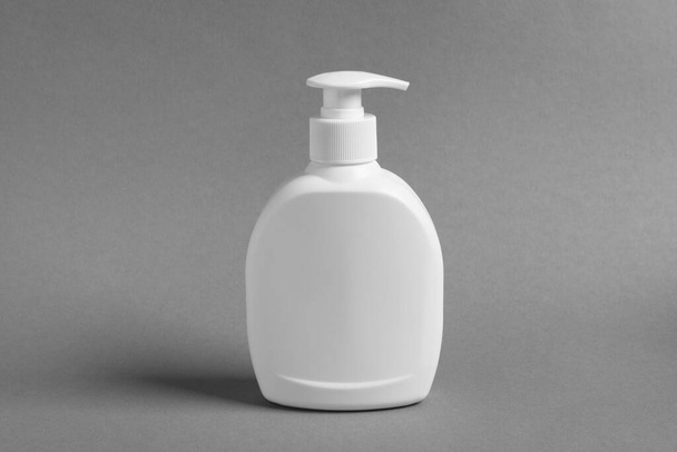 Bottle with cosmetic product on grey background - Foto, imagen