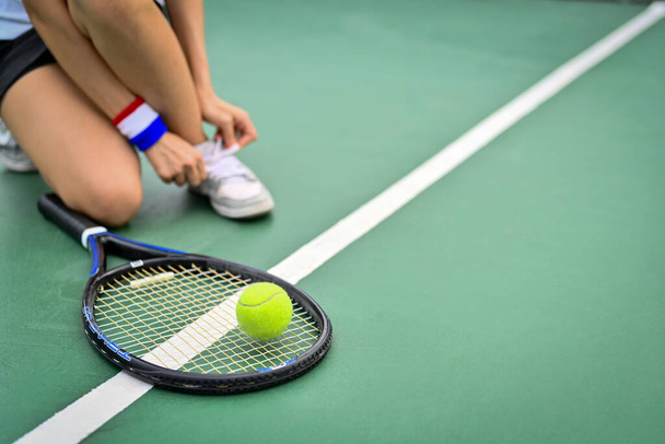 Przycięty obraz tenisisty wiążącego sznurowadło na korcie przygotowującego się do meczu. Sport, aktywne życie, koncepcja zawodów. - Zdjęcie, obraz