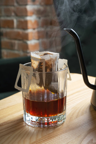 Drip coffee in a glass cup with a teapot on a wooden table in a beautiful interior. - 写真・画像