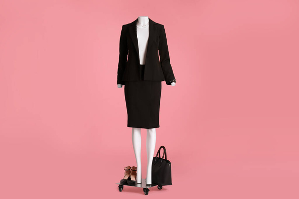 Female mannequin with accessories and shoes dressed in black classic suit on pink background. Stylish outfit - Foto, immagini