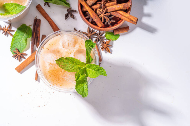 Thai Iced tea, asian indian masala spices drink with non-dairy coconut whipped milk, ice cubes and mint leaves, copy space - Foto, immagini