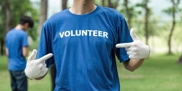 Закройте, молодой человек, добровольно напяливающий футболку с сообщением добровольца. - Фото, изображение