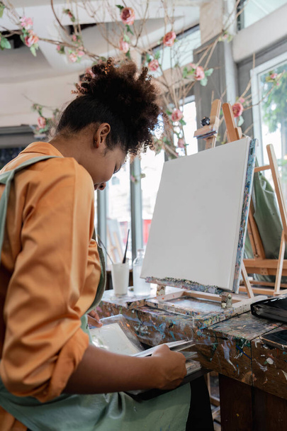 Belle artiste afro-américaine peinture confiante sur toile au studio d'art. - Photo, image