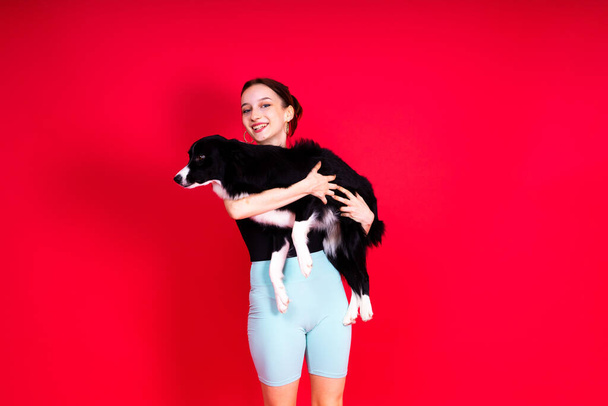Portrait of female posing with border collie in studio, yellow and red background - Photo, Image