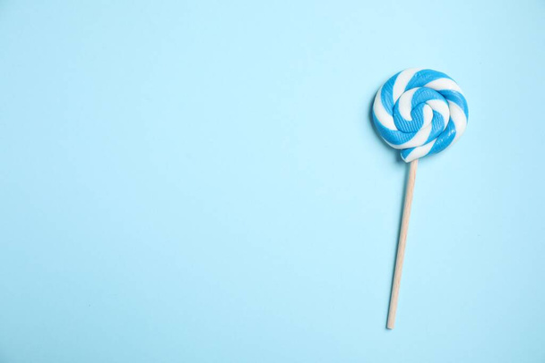 Stick with bright lollipop on light blue background, top view. Space for text - Foto, Imagem