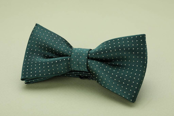 Stylish bow tie with polka dot pattern on pale green background, closeup - Fotó, kép