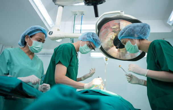 Equipo de cirujanos profesionales asiáticos que realiza cirugía en el quirófano, cirujano, asistentes y enfermeras que realizan cirugía en un paciente, el cáncer de atención médica y el concepto de tratamiento de enfermedades - Foto, imagen