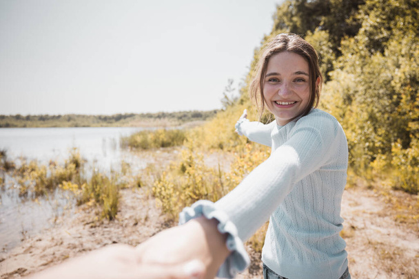 A young attractive woman taking her lover hand in hand leading to the lakeside during sunset by pov camera angle . High quality photo - Foto, imagen