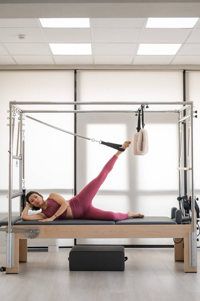 Asian woman doing pilates exercise on cadillac reformer machine - Foto, Imagen