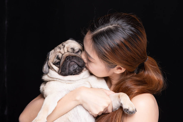 Asian woman hugging dog pud breed with love happiness emotional isolated on black background - 写真・画像
