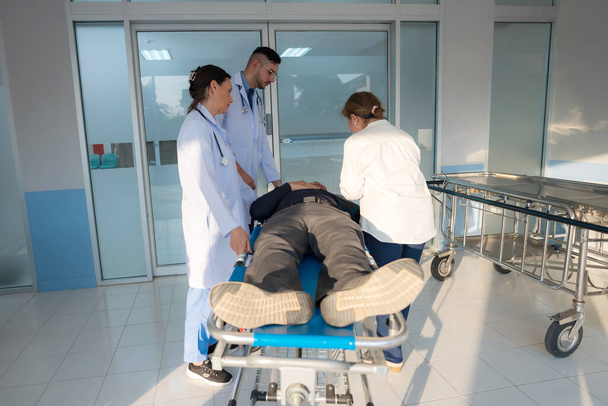 Il paziente di emergenza si trova in un letto d'ospedale con un medico che esegue un esame urgente. - Foto, immagini