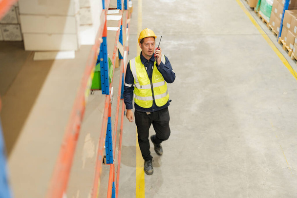Male employee using a radio in the warehouse to inspect the product to meet the needs of customers. - Fotoğraf, Görsel