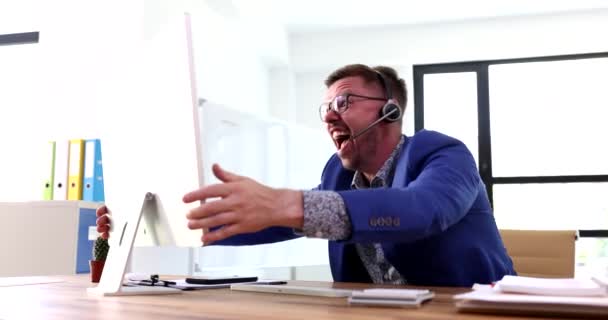 Üzletember fülhallgatóban kiabál a számítógép képernyőjén, és középső ujj 4K filmet mutat. A távmunka koncepciójának problémái és nehézségei - Felvétel, videó