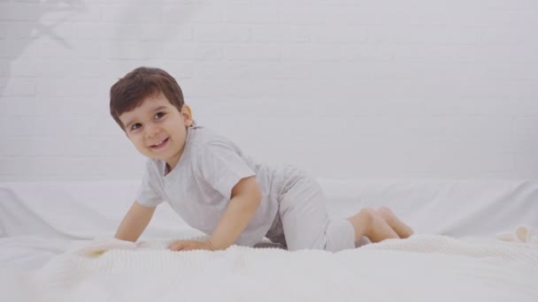 Caucasico bambino Buon divertimento saltare sul letto. Concetto di libertà, felicità e gioventù. - Filmati, video