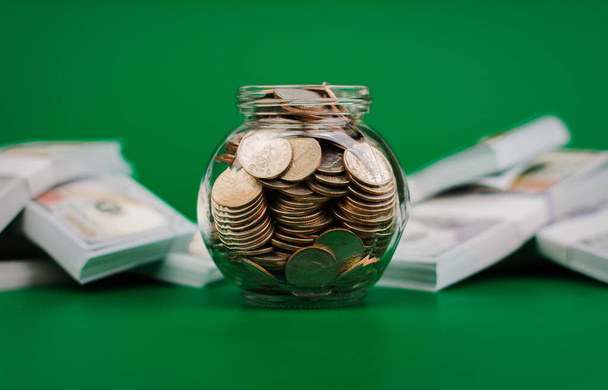 Money saving coins in a glass jar next to the dollar bill. financial income, salary, financial investment financial system savings concept - Photo, Image
