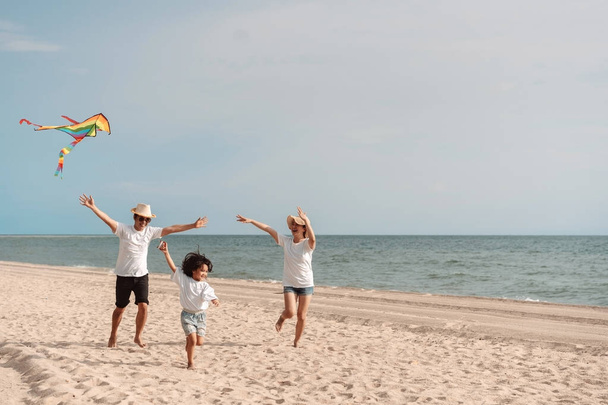 Happy asian family enjoy the sea beach. father, mother and daughter having fun playing beach in summer vacation on the ocean beach. Happy family with vacation time lifestyle concept. - Фото, зображення