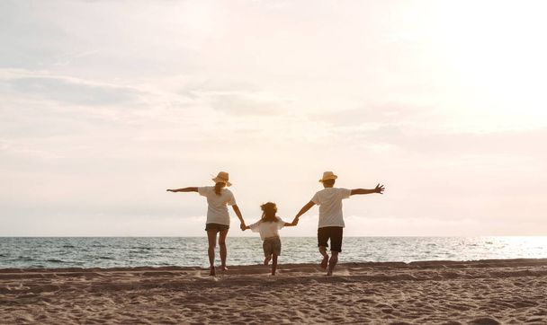 Happy asian family enjoy the sea beach. father, mother and daughter having fun playing beach in summer vacation on the ocean beach. Happy family with vacation time lifestyle concept. - Foto, Imagem