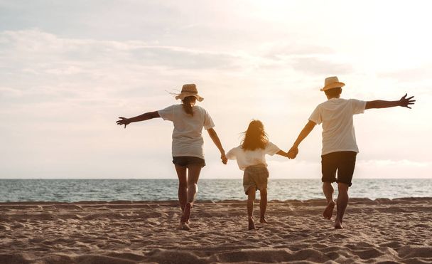 Happy asian family enjoy the sea beach. father, mother and daughter having fun playing beach in summer vacation on the ocean beach. Happy family with vacation time lifestyle concept. - Photo, image