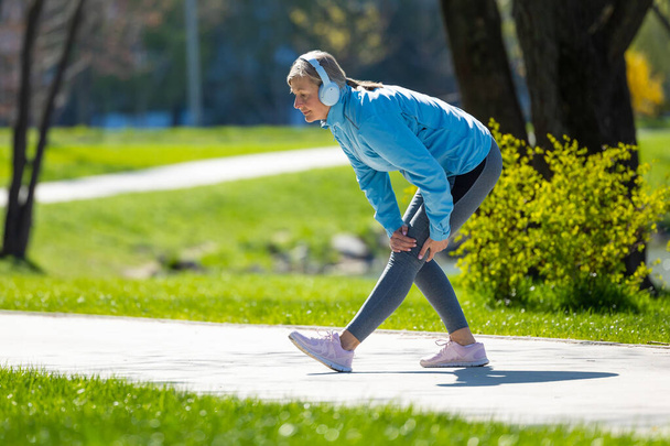 Workout. Woman in blue blazer doing leanings in the park - Foto, imagen