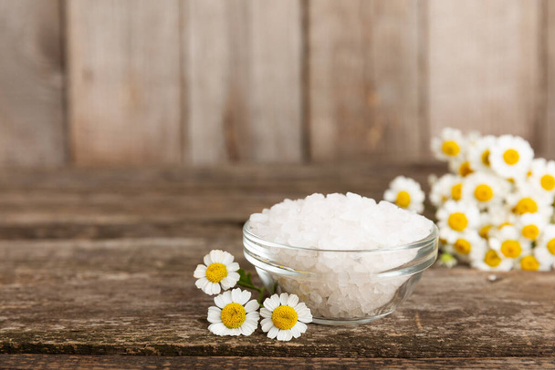 Sea bath salt with herbal chamomile extract on textured background. Salt in a glass jar. Body care cosmetics, natural organic product, herbal medicine. Beauty concept. Place for text. copy space. - 写真・画像
