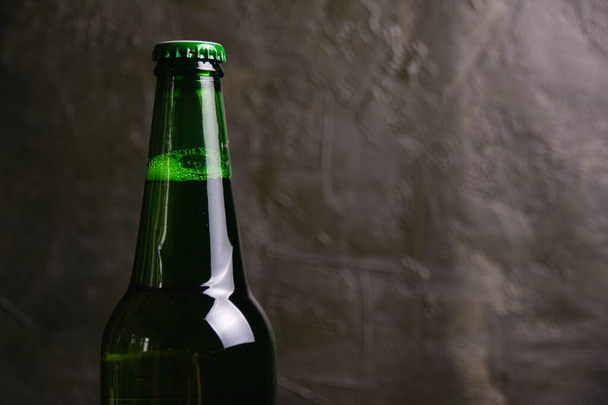 Aromatyczne piwo w szklanej butelce na ciemnym tle z przestrzenią do kopiowania. - Zdjęcie, obraz