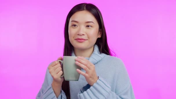 Coffee, funny and aroma with a happy asian woman in studio isolated on a pink background to relax. Smile, caffeine and drinking a beverage with a young female person enjoying a fresh cup of tea. - Footage, Video