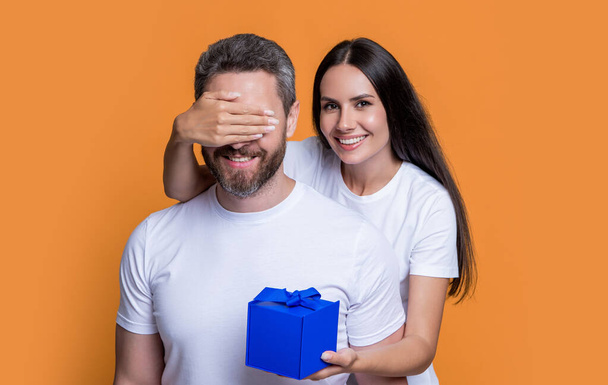 happy surprise couple with present in studio. holiday couple with present box. photo of couple with present for holiday surprise. mens day. couple with surprise present isolated on yellow background. - Fotoğraf, Görsel