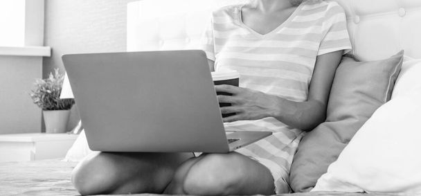 cropped view of woman freelancer with coffee work at home on laptop. freelancer woman work at home. home work for freelancer. woman in bed with laptop. - Zdjęcie, obraz