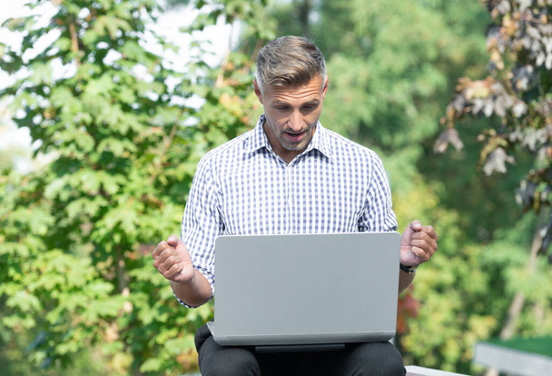 amazed freelancer working on laptop. man freelancer outdoor. business freelancer with pc. - Foto, afbeelding