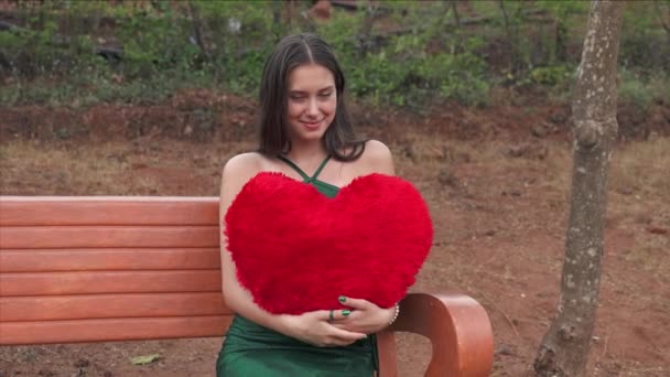 La mujer joven se acaricia hasta el corazón grande rojo - el concepto del Día de San Valentín. Video de alta calidad 4k - Imágenes, Vídeo