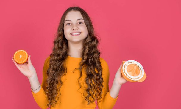 positive teen kid hold orange and juicer on pink background. - Φωτογραφία, εικόνα