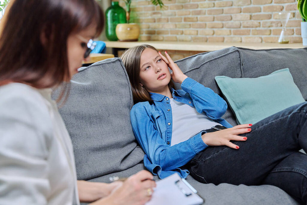 Sad young 20s woman in meeting with female psychologist therapist counselor sitting on couch in office. Psychology, therapy, psychotherapy, treatment, mental health concept - Foto, immagini