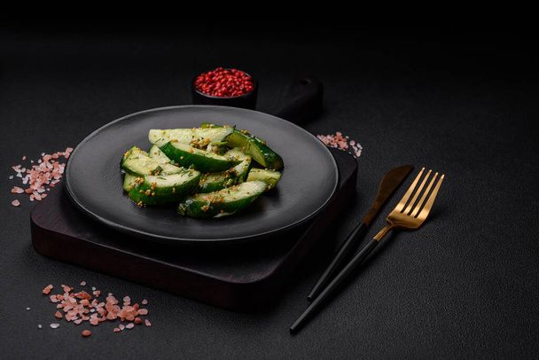 Delicious juicy cucumber cut into large slices with salt, spices and french mustard on a dark concrete background - Photo, Image