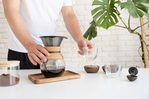 Man prepares coffee in style pour over at home kitchen - Fotó, kép