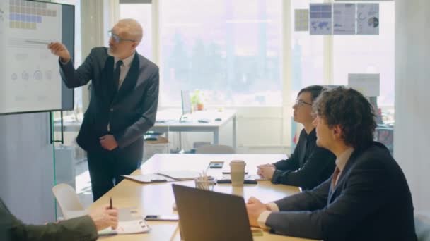 Vezető üzletember digitális táblát használ, miközben bemutatót tart a csapatnak az irodai vállalati találkozón - Felvétel, videó