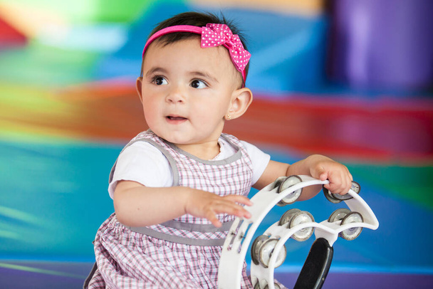 Hermosa niña de diez meses jugando con una pandereta. Estimulación temprana para el concepto de niños pequeños. - Foto, imagen