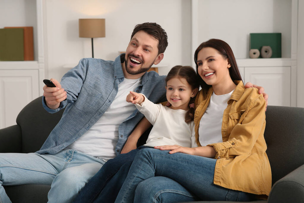 Familia feliz viendo películas en casa. Padre cambiando canales de TV con control remoto - Foto, Imagen