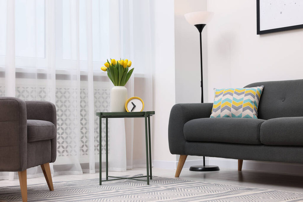 Spring atmosphere. Stylish living room interior with comfortable furniture and bouquet of beautiful yellow tulips - Φωτογραφία, εικόνα