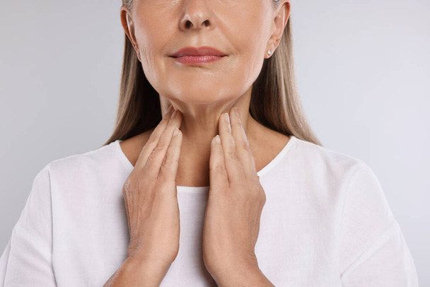 Endocrine system. Senior woman doing thyroid self examination on light grey background, closeup - Φωτογραφία, εικόνα