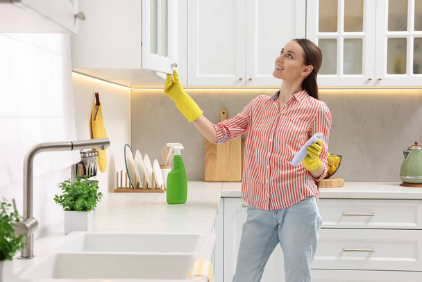 Spring cleaning. Young woman tidying up kitchen at home - Фото, зображення