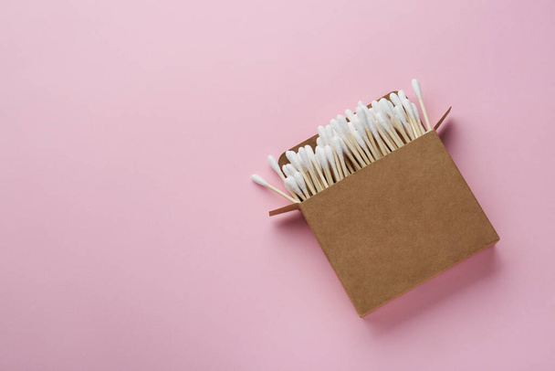 Cotton buds in cardboard box on pink background, top view. Space for text - Photo, image