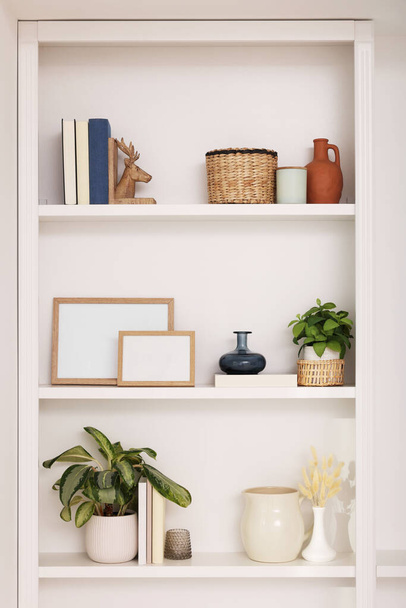 Interior design. Shelves with stylish accessories, potted plants and frames near white wall - Foto, immagini