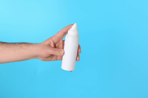 Man holding nasal spray on light blue background, closeup. Space for text - Foto, imagen